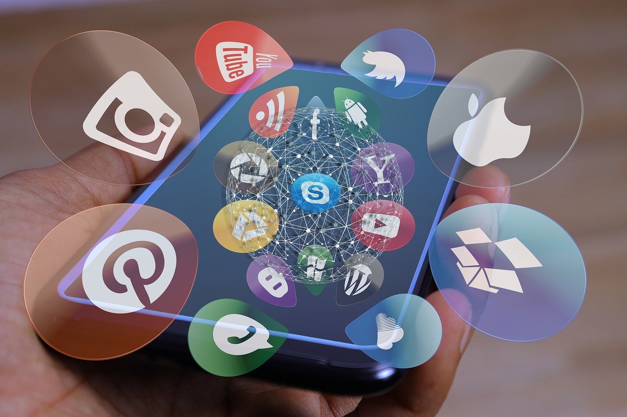  A hand holding a smartphone with various social media platform logos on the screen representing the search query 'Social media marketing trends emerging platforms algorithm agility AI integration ethics in marketing'.